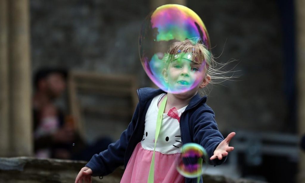 PORTHMADOG, UNITED KINGDOM - SEPTEMBER 15: A young girl catches giant soap bubbles during The Number Six Festival on September 15, 2012 in Porthmadog, United Kingdom. The classic Italianate village of Portmeirion in North Wales is staging the first ever No. 6 Festival, named after the famous 1960's cult TV series ''The Prisoner'' which was filmed in the village. The three day festival is a kaleidoscope of entertainment with music, art and performances ranging from poetry to pop and classical music.. (Photo by Christopher Furlong/Getty Images)